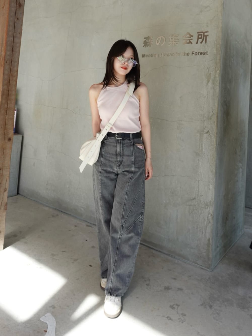 ブラック系のデニムパンツ、ホワイト系のスニーカー、ホワイト系のタンクトップを着用したレディースの秋コーディネートの2枚目の写真