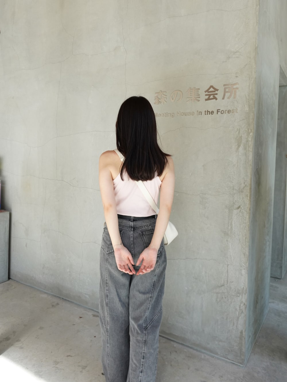 ブラック系のデニムパンツ、ホワイト系のスニーカー、ホワイト系のタンクトップを着用したレディースの秋コーディネートの3枚目の写真