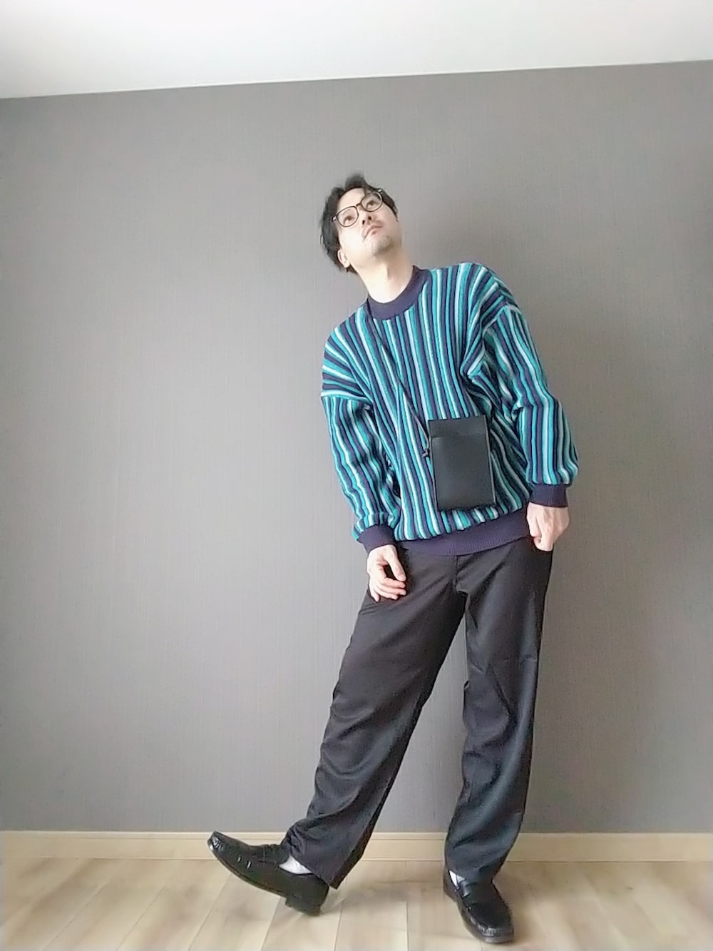 ブラック系のスラックス、ブラック系のローファー、ブルー系のニット/セーターを着用したメンズの春コーディネートの3枚目の写真