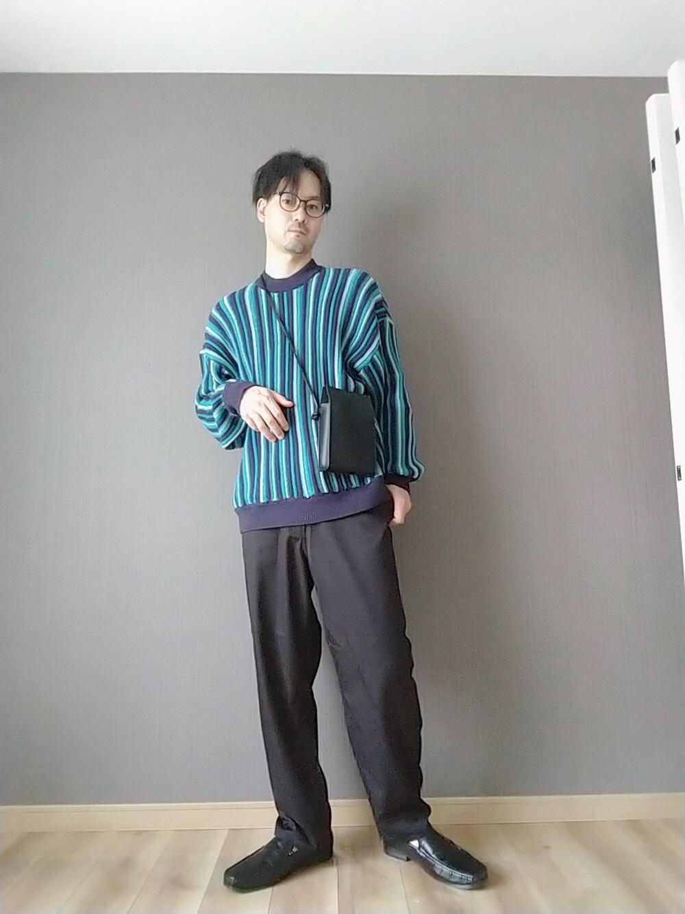 ブラック系のスラックス、ブラック系のローファー、ブルー系のニット/セーターを着用したメンズの春コーディネートの2枚目の写真