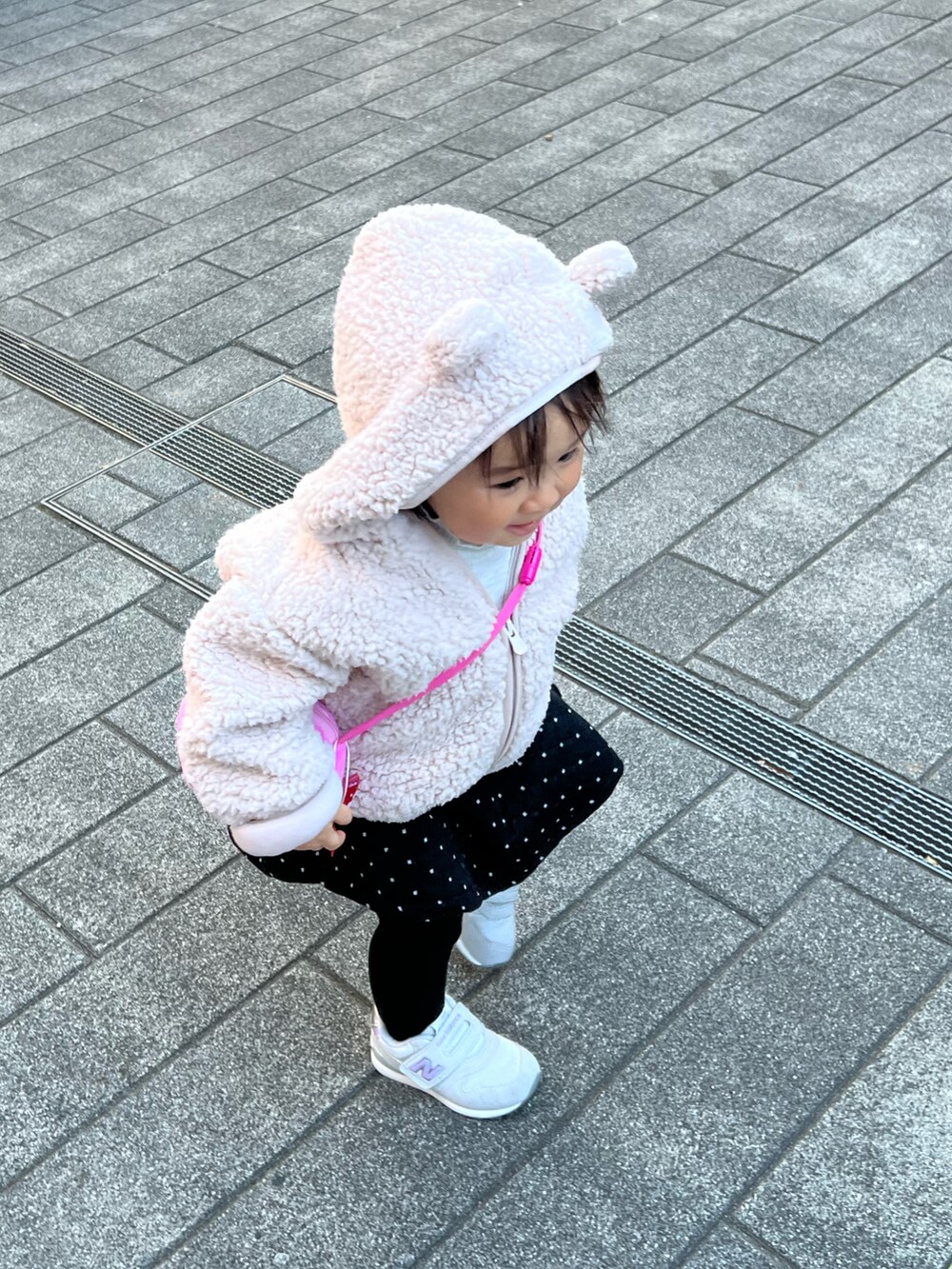 ピンク系のパーカー、ブラック系のワンピース、グレー系のスニーカーを着用したキッズの冬コーディネートの2枚目の写真