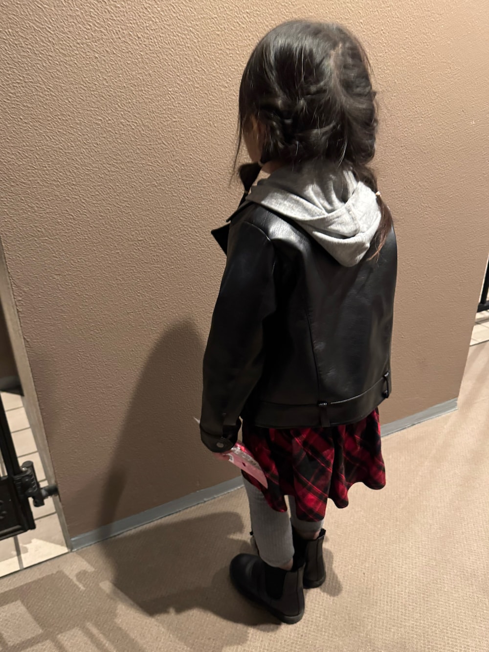 ブラック系のブーツ、ブラック系のライダースジャケット、レッド系のワンピースを着用したキッズの冬コーディネートの3枚目の写真