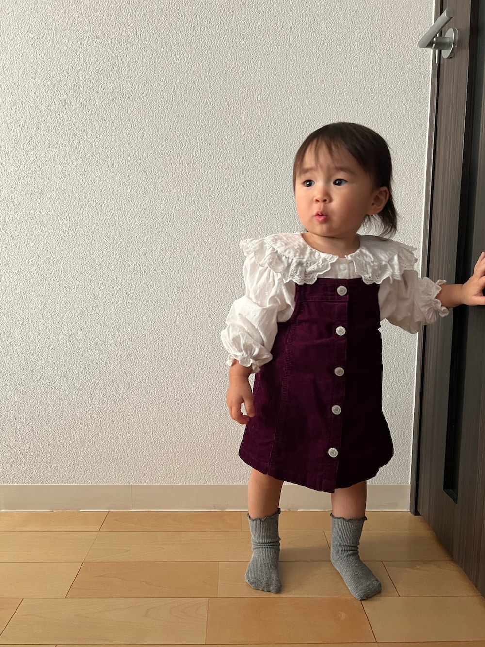 レッド系のジャンパースカート、ホワイト系のシャツ/ブラウス、グレー系のソックス/靴下を着用したキッズの秋コーディネートの4枚目の写真