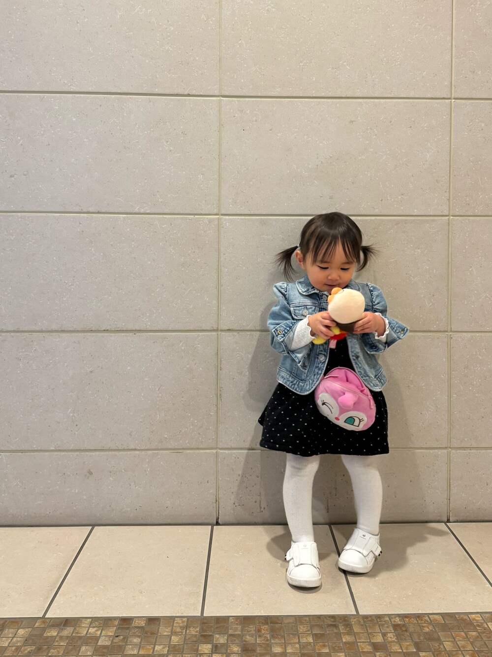 ブルー系のデニムジャケット、ブラック系のワンピース、ホワイト系のスニーカーを着用したキッズの春コーディネートの3枚目の写真