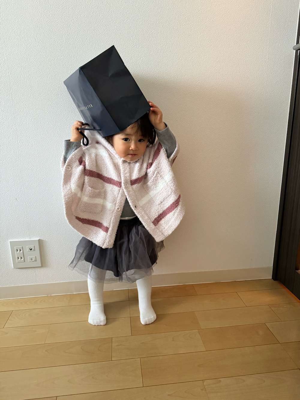 ピンク系のポンチョ、グレー系のTシャツ/カットソー、グレー系のスカートを着用したキッズの冬コーディネートの3枚目の写真