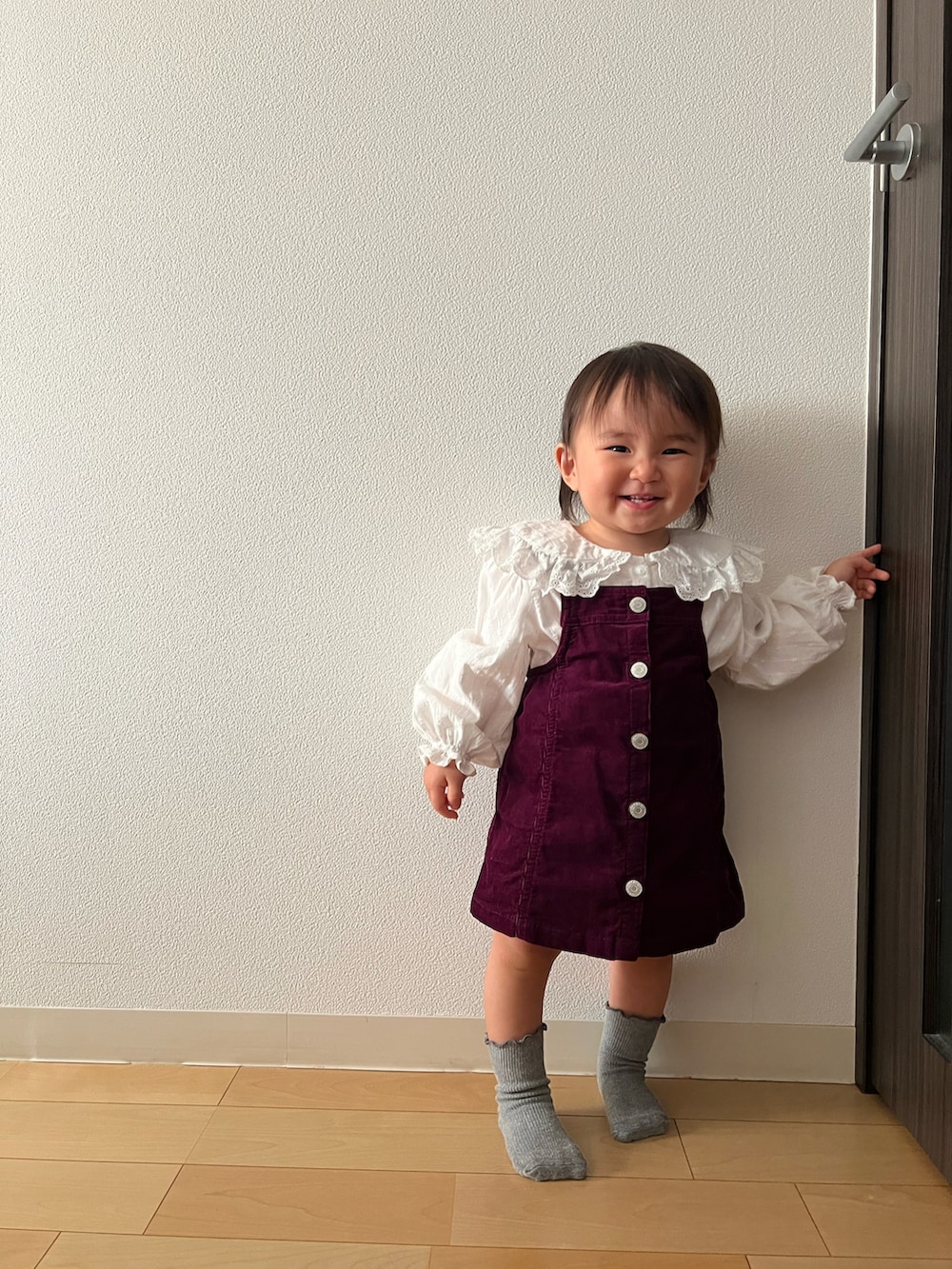 レッド系のジャンパースカート、ホワイト系のシャツ/ブラウス、グレー系のソックス/靴下を着用したキッズの秋コーディネートの3枚目の写真