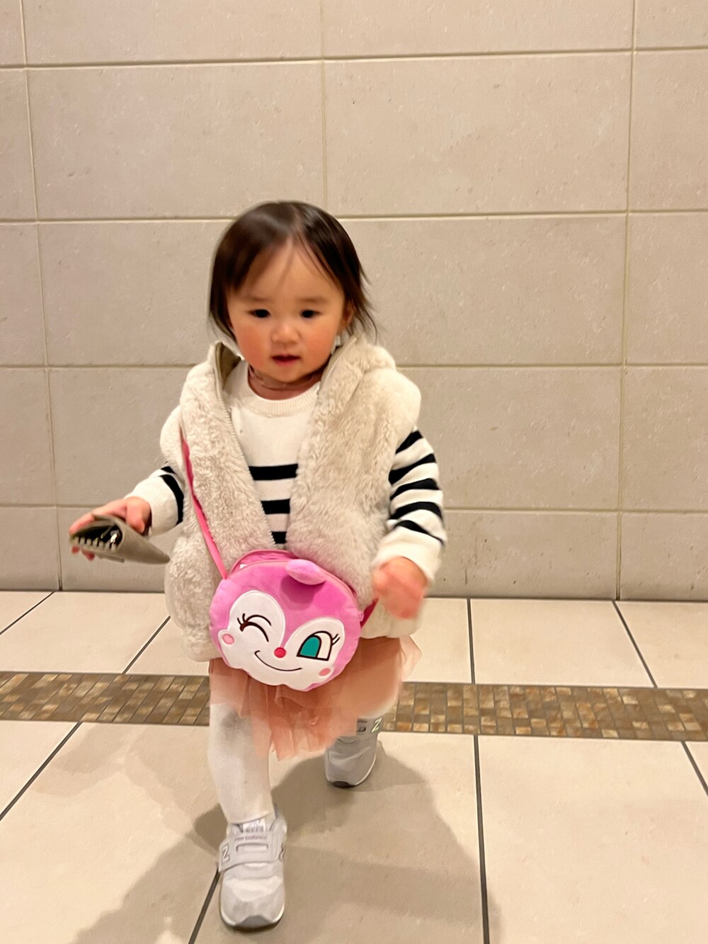 ベージュ系のベスト、ベージュ系のニット/セーター、ピンク系のワンピースを着用したキッズの冬コーディネートの3枚目の写真