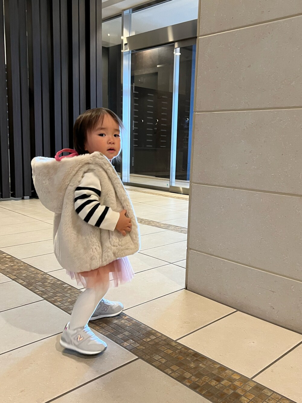 ベージュ系のベスト、ベージュ系のニット/セーター、ピンク系のワンピースを着用したキッズの冬コーディネートの2枚目の写真