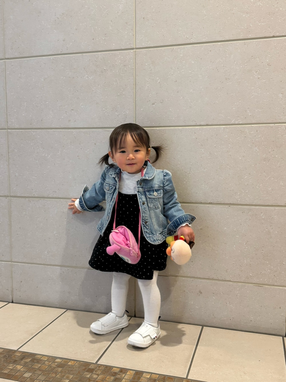 ブルー系のデニムジャケット、ブラック系のワンピース、ホワイト系のスニーカーを着用したキッズの春コーディネートの2枚目の写真