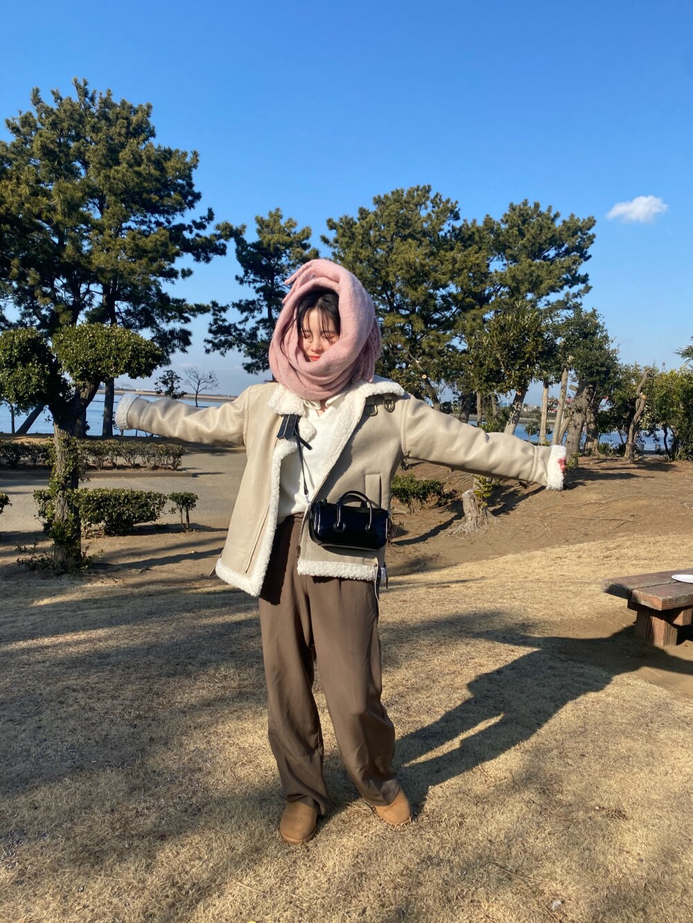 ベージュ系のムートンコート、ピンク系のマフラーを着用したレディースの冬コーディネートの3枚目の写真