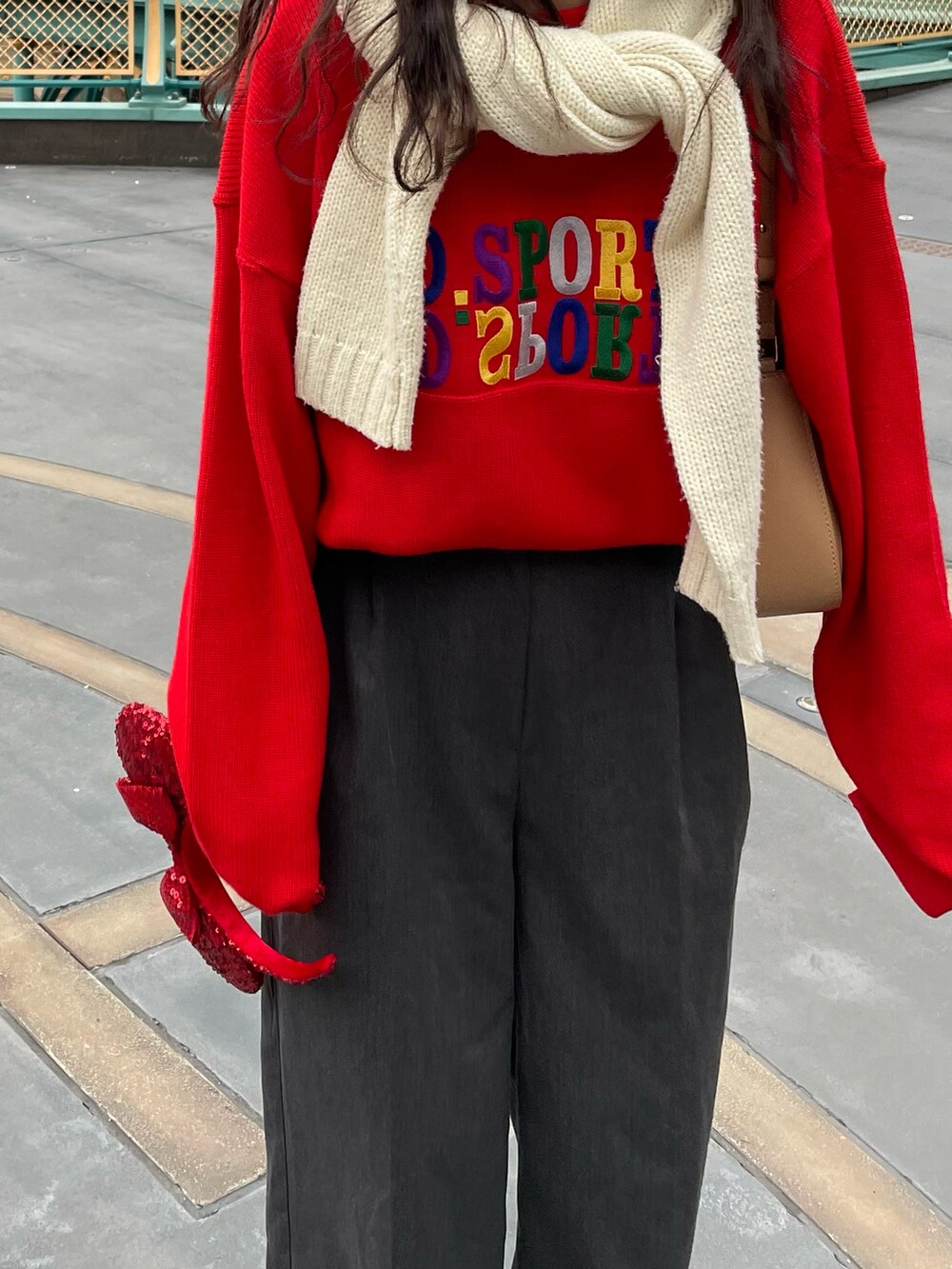 ホワイト系のスニーカー、グレー系のスラックス、レッド系のスウェットを着用したレディースの春コーディネートの2枚目の写真
