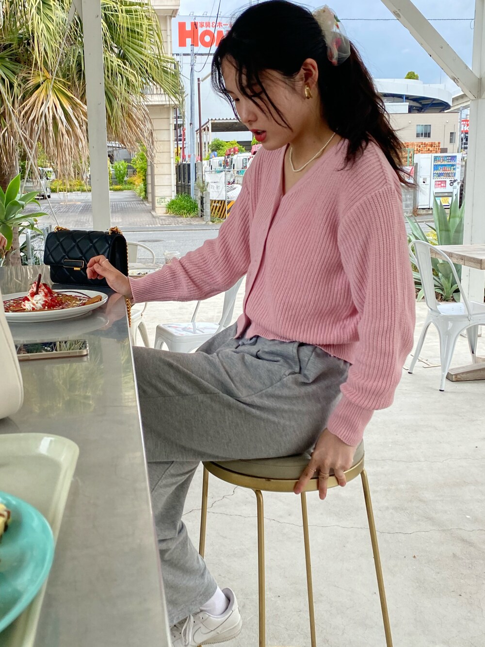 ピンク系のカーディガン/ボレロ、ブラック系のバッグ、シルバー系のパンツを着用したレディースの春コーディネートの2枚目の写真