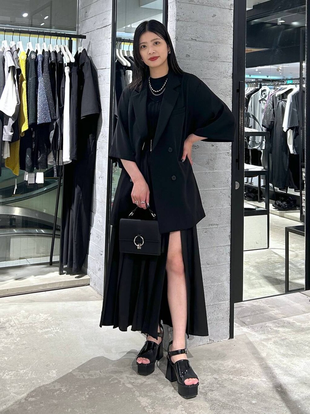 ブラック系のサンダル、ブラック系のテーラードジャケット、ブラック系のショルダーバッグを着用したレディースの春コーディネートの2枚目の写真