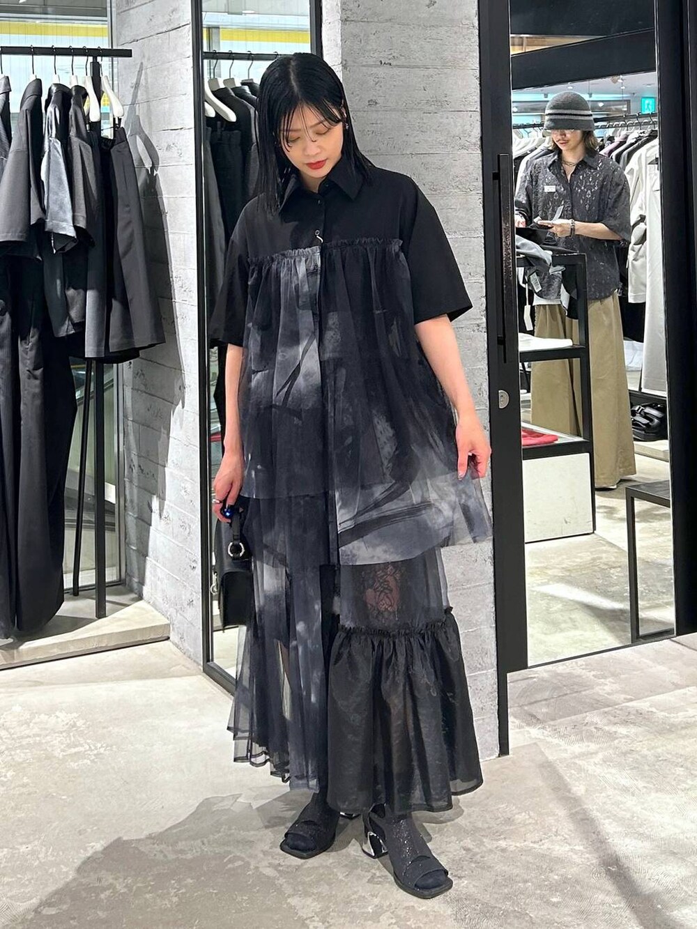 ブラック系のサンダル、ブラック系のショルダーバッグ、ブラック系のシャツ/ブラウスを着用したレディースの夏コーディネートの3枚目の写真