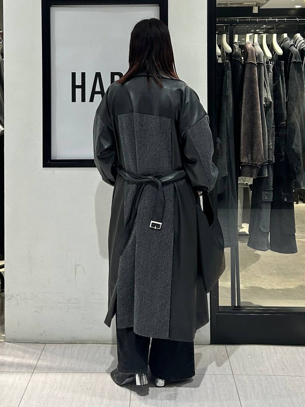 ブラック系のチェスターコート、ブラック系のデニムパンツ、ブラック系のトートバッグを着用したレディースの秋コーディネートの4枚目の写真