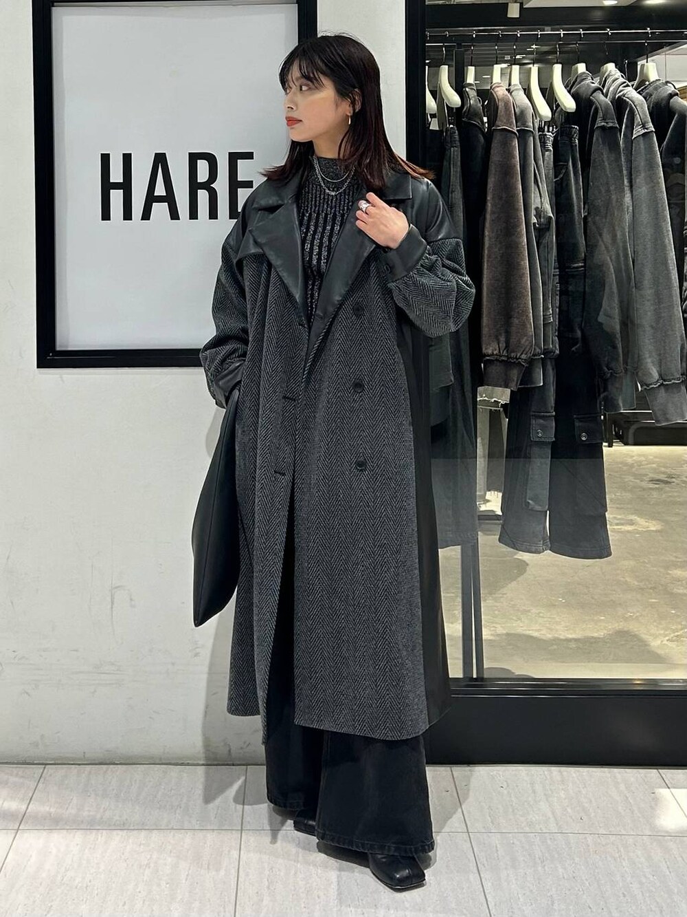 ブラック系のチェスターコート、ブラック系のデニムパンツ、ブラック系のトートバッグを着用したレディースの秋コーディネートの2枚目の写真