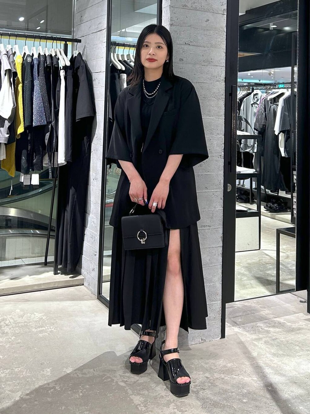 ブラック系のサンダル、ブラック系のテーラードジャケット、ブラック系のショルダーバッグを着用したレディースの春コーディネートの3枚目の写真