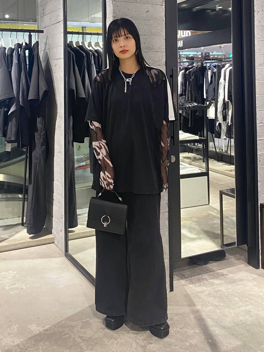 ブラック系のデニムパンツ、ブラック系のショルダーバッグ、ブラック系のパンプスを着用したレディースの夏コーディネートの3枚目の写真