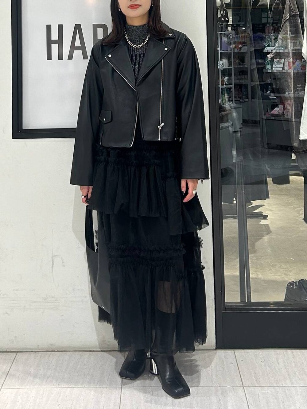 ブラック系のトートバッグ、ブラック系のニット/セーター、ブラック系のブーツを着用したレディースの秋コーディネートの3枚目の写真