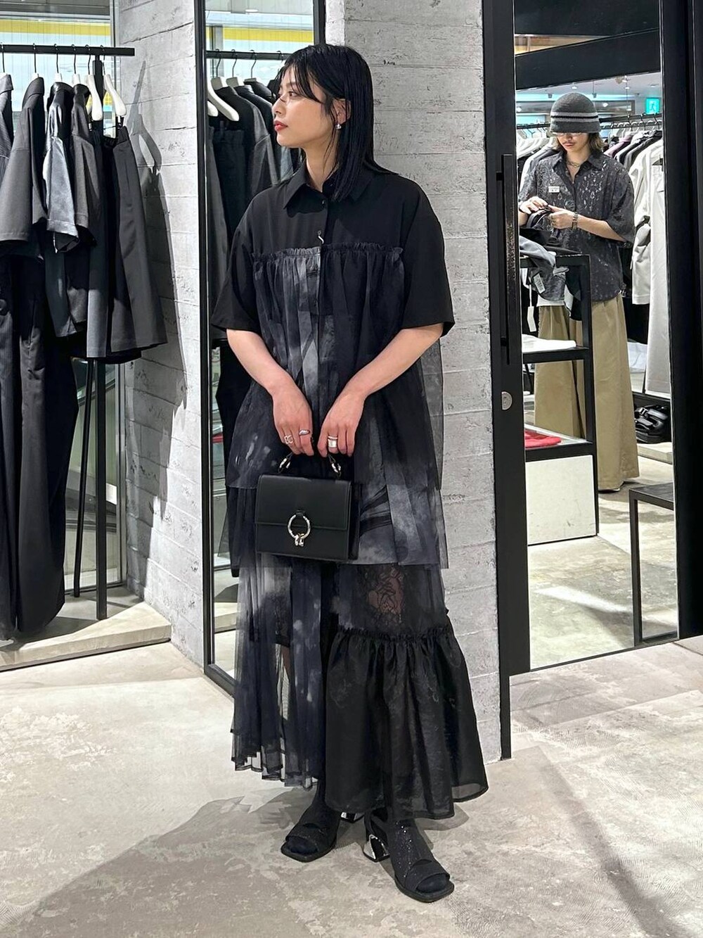 ブラック系のサンダル、ブラック系のショルダーバッグ、ブラック系のシャツ/ブラウスを着用したレディースの夏コーディネートの2枚目の写真