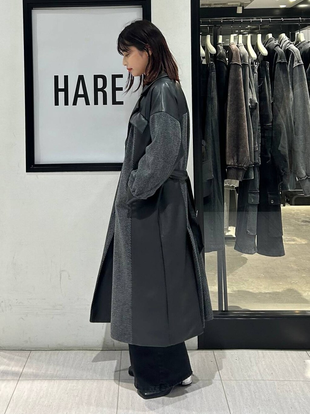 ブラック系のチェスターコート、ブラック系のデニムパンツ、ブラック系のトートバッグを着用したレディースの秋コーディネートの3枚目の写真