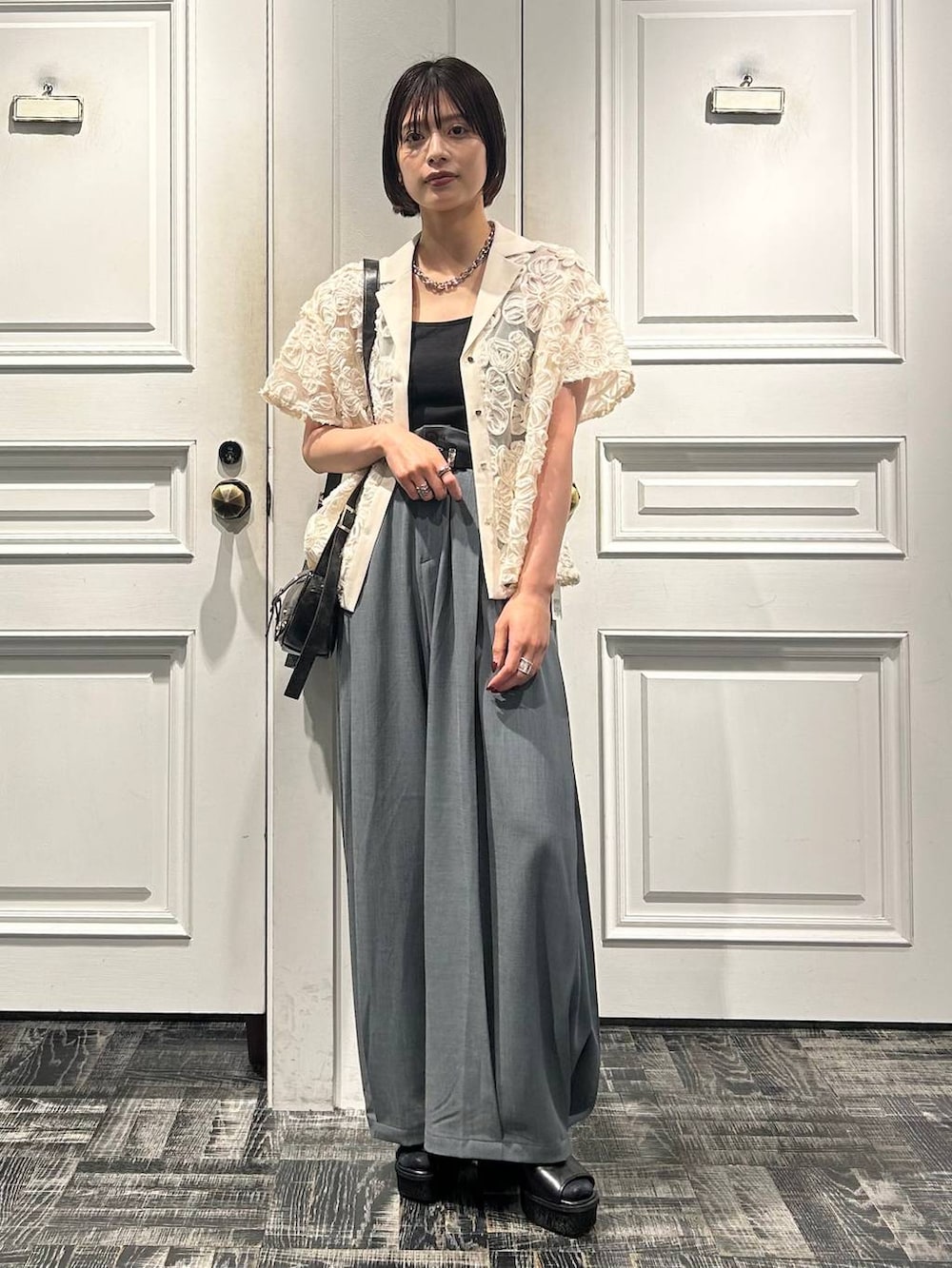 グレー系のショルダーバッグ、グレー系のサンダル、ホワイト系のシャツ/ブラウスを着用したレディースの春コーディネートの2枚目の写真