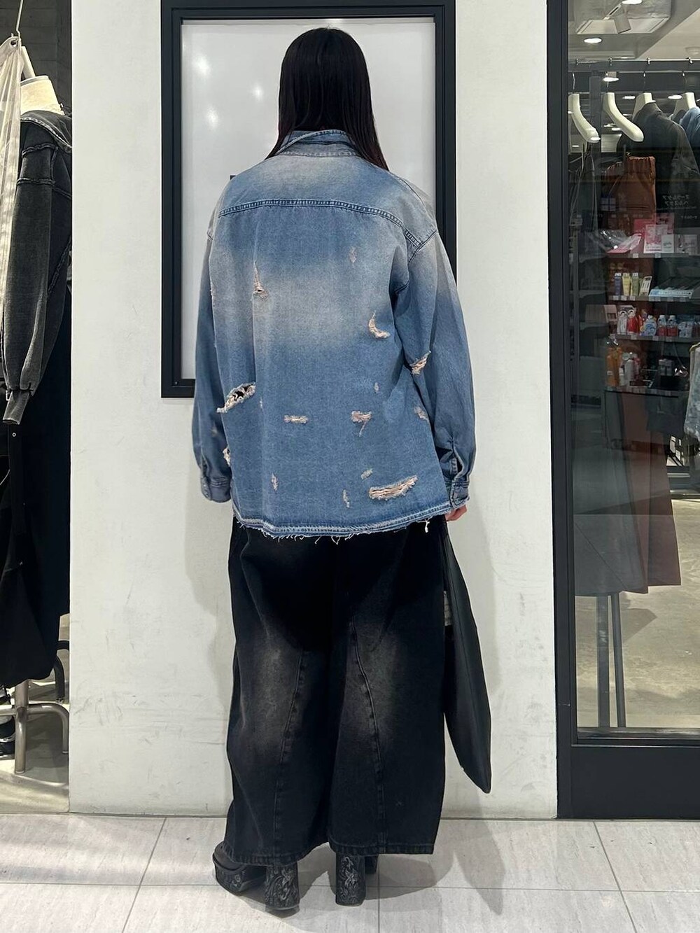 ブラック系のトートバッグ、ブラック系のデニムパンツ、ブラック系のパンプスを着用したレディースの冬コーディネートの5枚目の写真