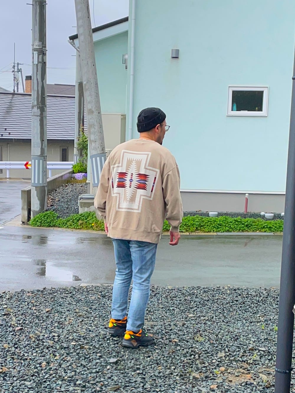 ベージュ系のスウェット、ブラック系のスニーカー、ブルー系のパンツを着用したメンズの春コーディネートの2枚目の写真