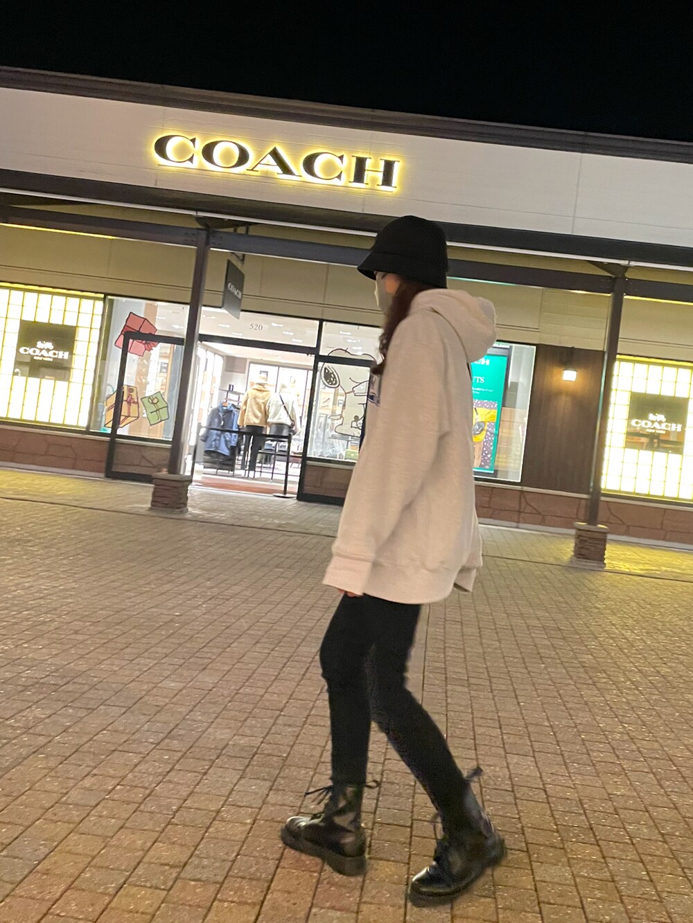 シルバー系のパーカー、ブラック系のデニムパンツ、ブラック系のブーツを着用したレディースの秋コーディネートの2枚目の写真