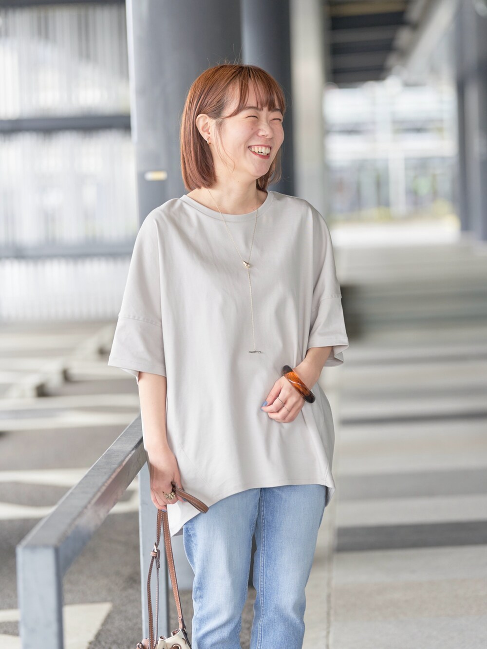ブルー系のデニムパンツ、ベージュ系のTシャツ/カットソー、ゴールド系のネックレスを着用したレディースの春コーディネートの4枚目の写真