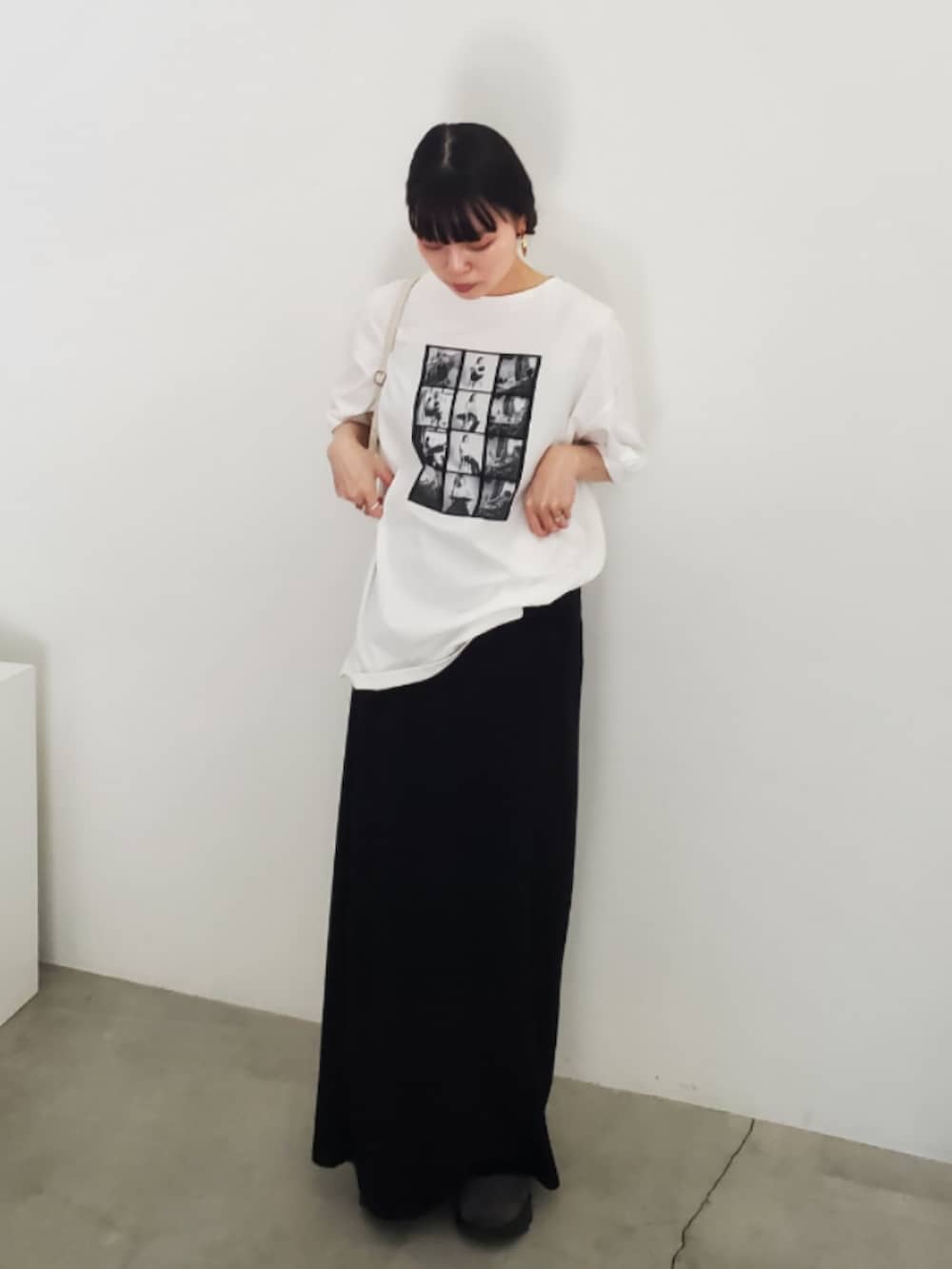 ホワイト系のTシャツ/カットソー、ブラック系のスカート、グレー系のスニーカーを着用したレディースの夏コーディネートの2枚目の写真