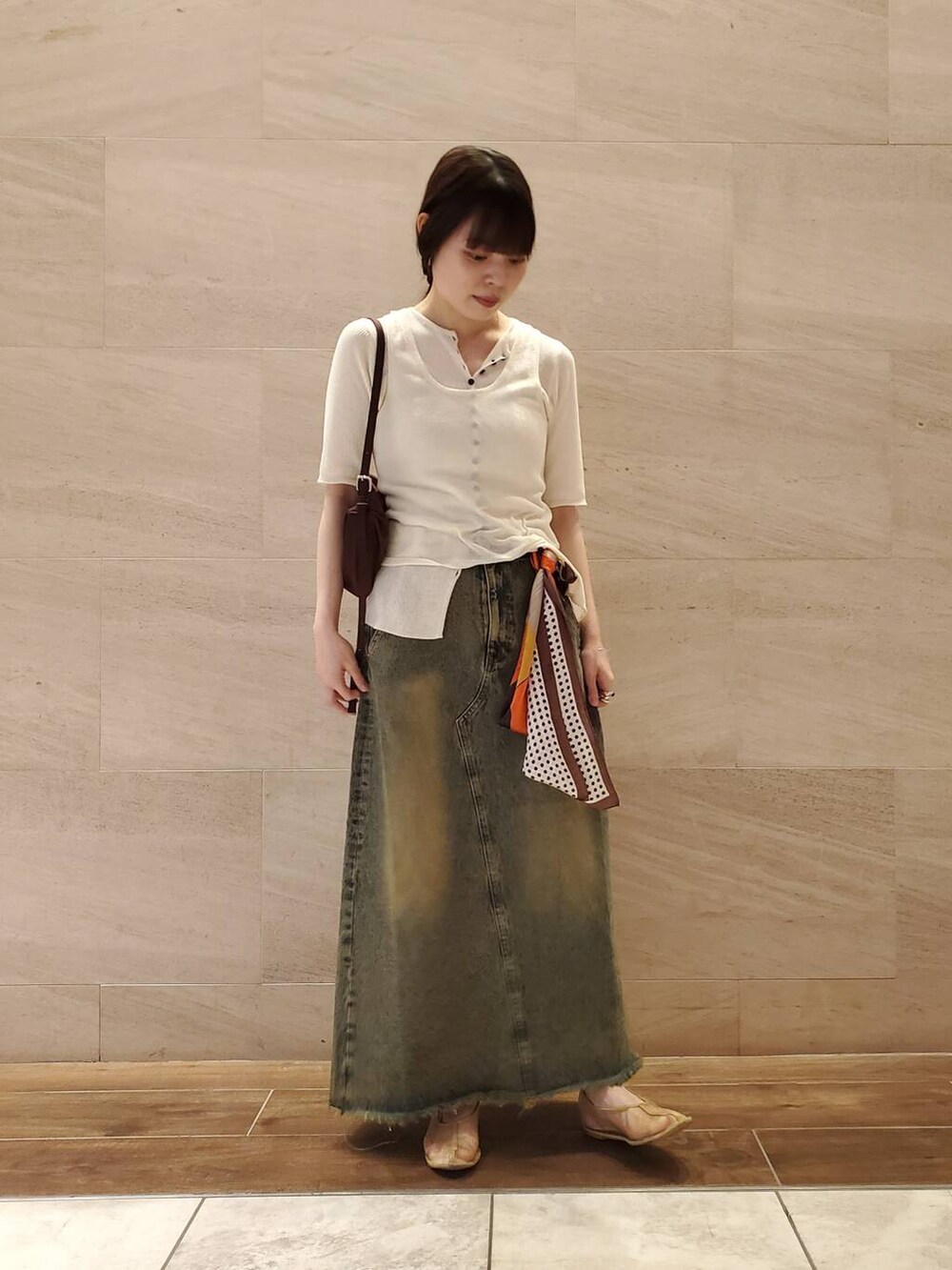 ブルー系のスカート、ホワイト系のニット/セーター、ブラウン系のバンダナ/スカーフを着用したレディースの夏コーディネートの3枚目の写真