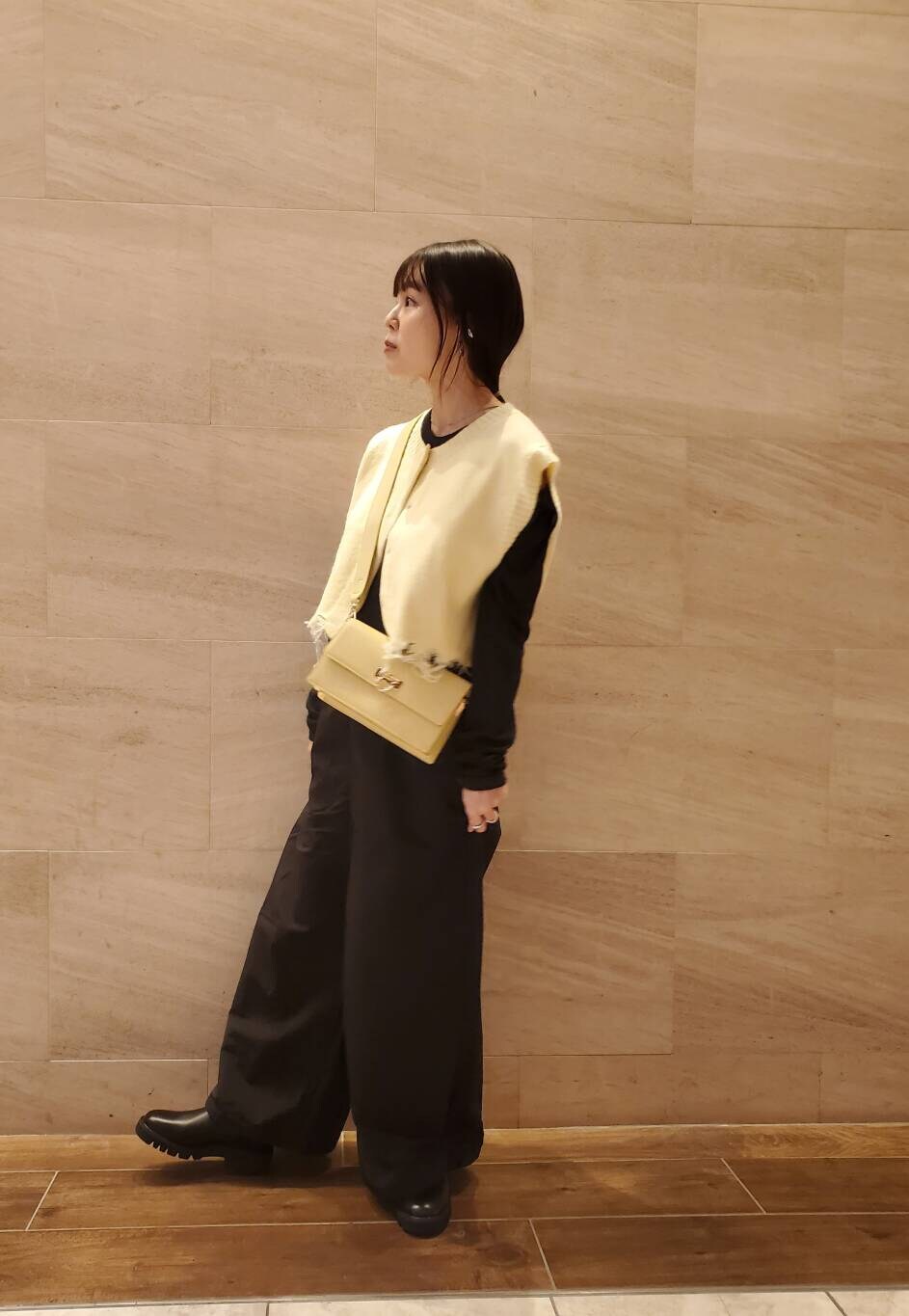 イエロー系のベストを着用したレディースの秋コーディネートの2枚目の写真
