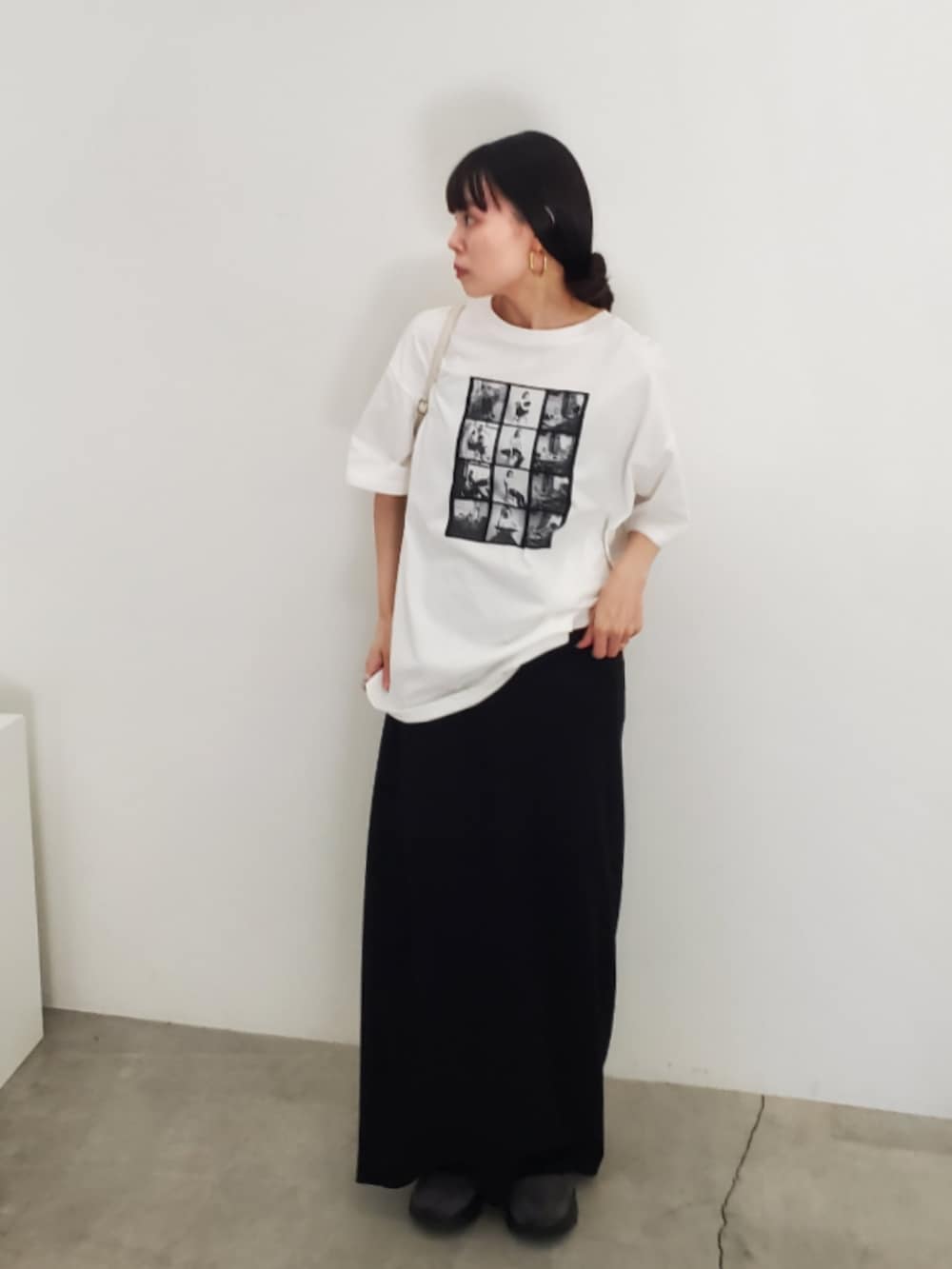 ホワイト系のTシャツ/カットソー、ブラック系のスカート、グレー系のスニーカーを着用したレディースの夏コーディネートの3枚目の写真