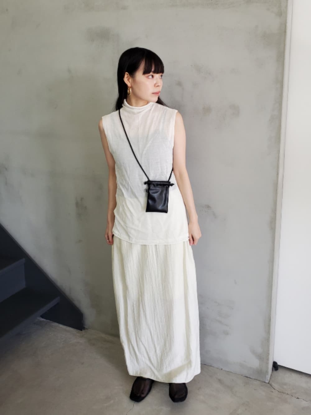 ホワイト系のニット/セーター、ベージュ系のスカート、ブラック系のスリッポンを着用したレディースの夏コーディネートの2枚目の写真