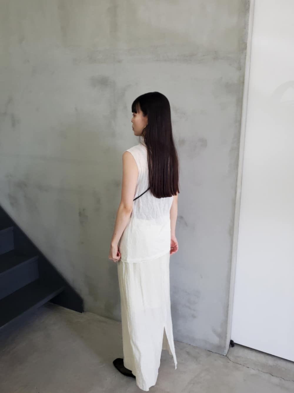 ホワイト系のニット/セーター、ベージュ系のスカート、ブラック系のスリッポンを着用したレディースの夏コーディネートの4枚目の写真