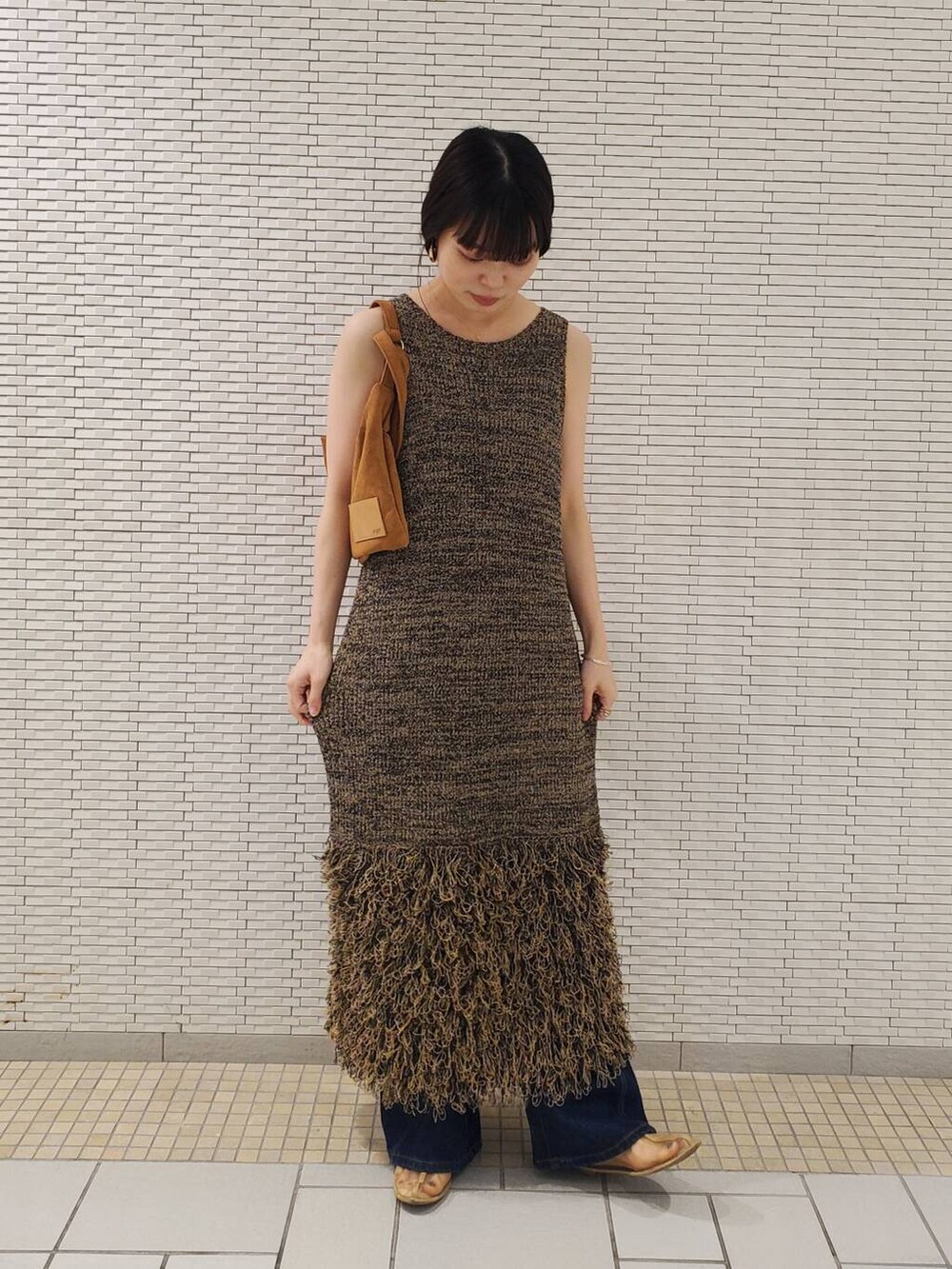 ベージュ系のワンピース、ブルー系のデニムパンツを着用したレディースの夏コーディネートの2枚目の写真