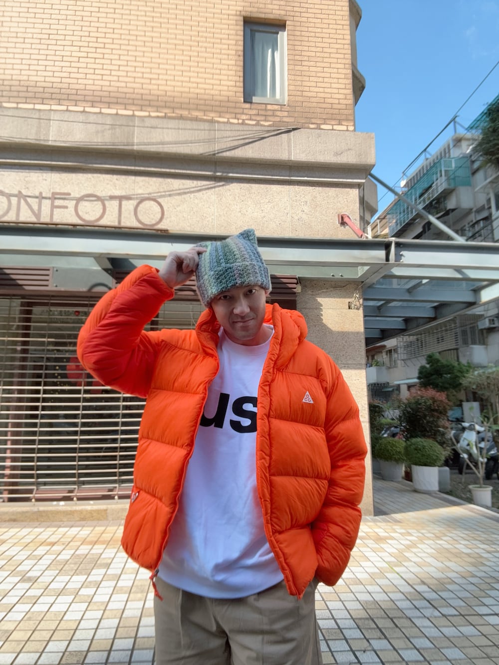 オレンジ系のダウンジャケット/コート、ホワイト系のTシャツ/カットソー、ベージュ系のチノパンツを着用したメンズの冬コーディネートの3枚目の写真