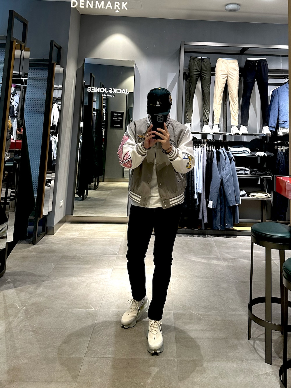 グレー系のスタジャン、ブラック系のデニムパンツ、ブラック系のスニーカーを着用したメンズの冬コーディネートの4枚目の写真