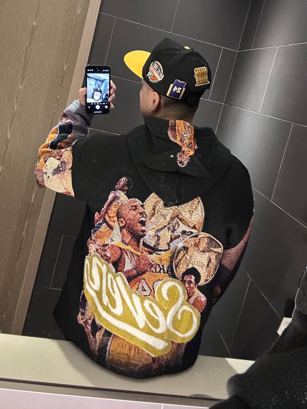 ブラック系のパーカー、ブラック系のスニーカー、ブルー系のデニムパンツを着用したメンズの冬コーディネートの3枚目の写真