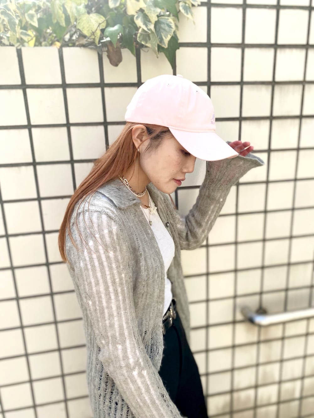 ブラック系のスラックス、ブルー系のスニーカー、ピンク系のキャップを着用したレディースの春コーディネートの2枚目の写真