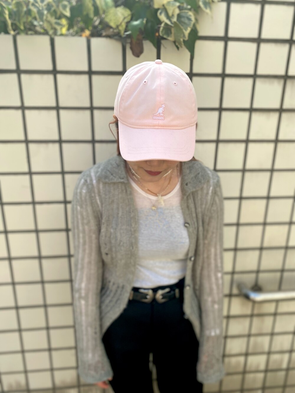 ブラック系のスラックス、ブルー系のスニーカー、ピンク系のキャップを着用したレディースの春コーディネートの3枚目の写真