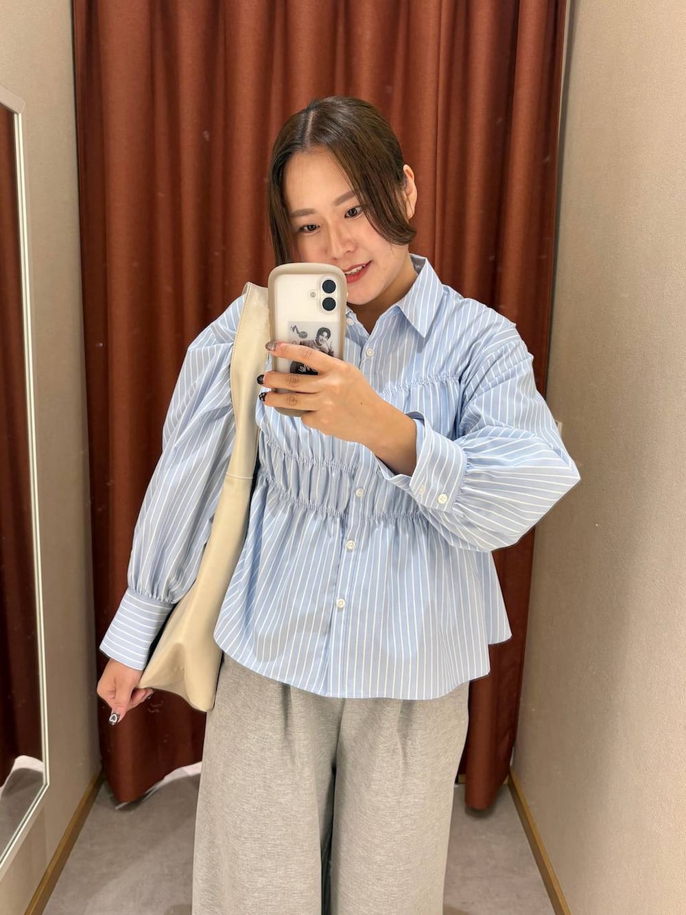 ホワイト系のショルダーバッグ、ホワイト系のパンプス、ブルー系のシャツ/ブラウスを着用したレディースの冬コーディネートの3枚目の写真