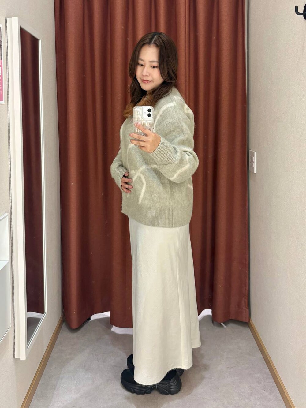 ホワイト系のスカート、ブラック系のスニーカー、グリーン系のニット/セーターを着用したレディースの秋コーディネートの2枚目の写真