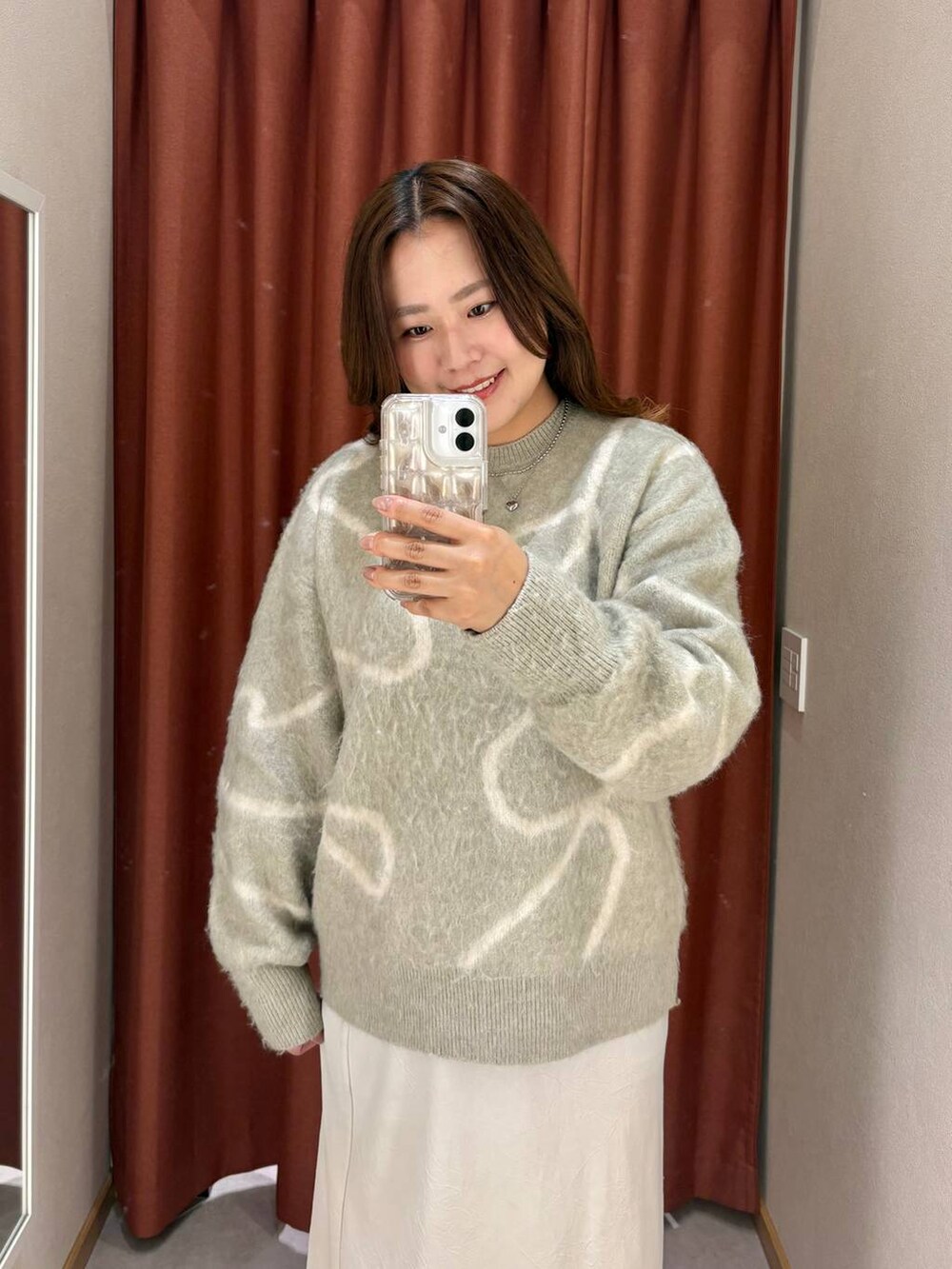 ホワイト系のスカート、ブラック系のスニーカー、グリーン系のニット/セーターを着用したレディースの秋コーディネートの3枚目の写真