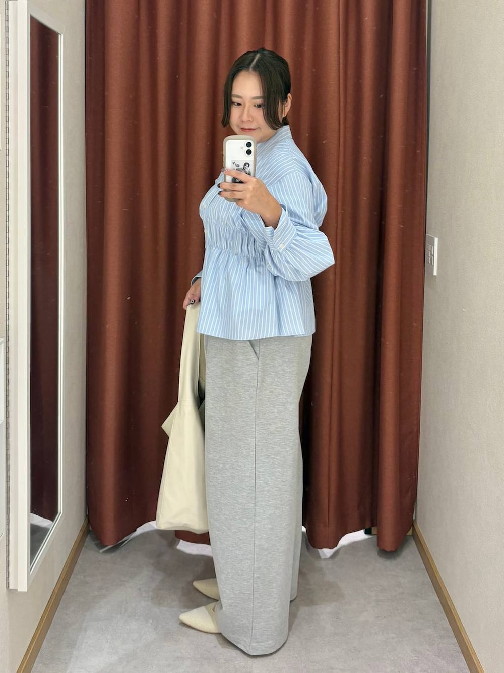 ホワイト系のショルダーバッグ、ホワイト系のパンプス、ブルー系のシャツ/ブラウスを着用したレディースの冬コーディネートの2枚目の写真