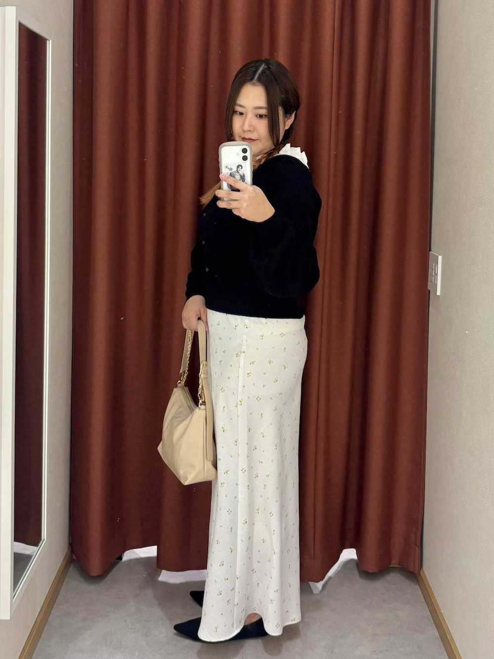 ホワイト系のスカート、ベージュ系のショルダーバッグ、ブラック系のパンプスを着用したレディースの冬コーディネートの2枚目の写真