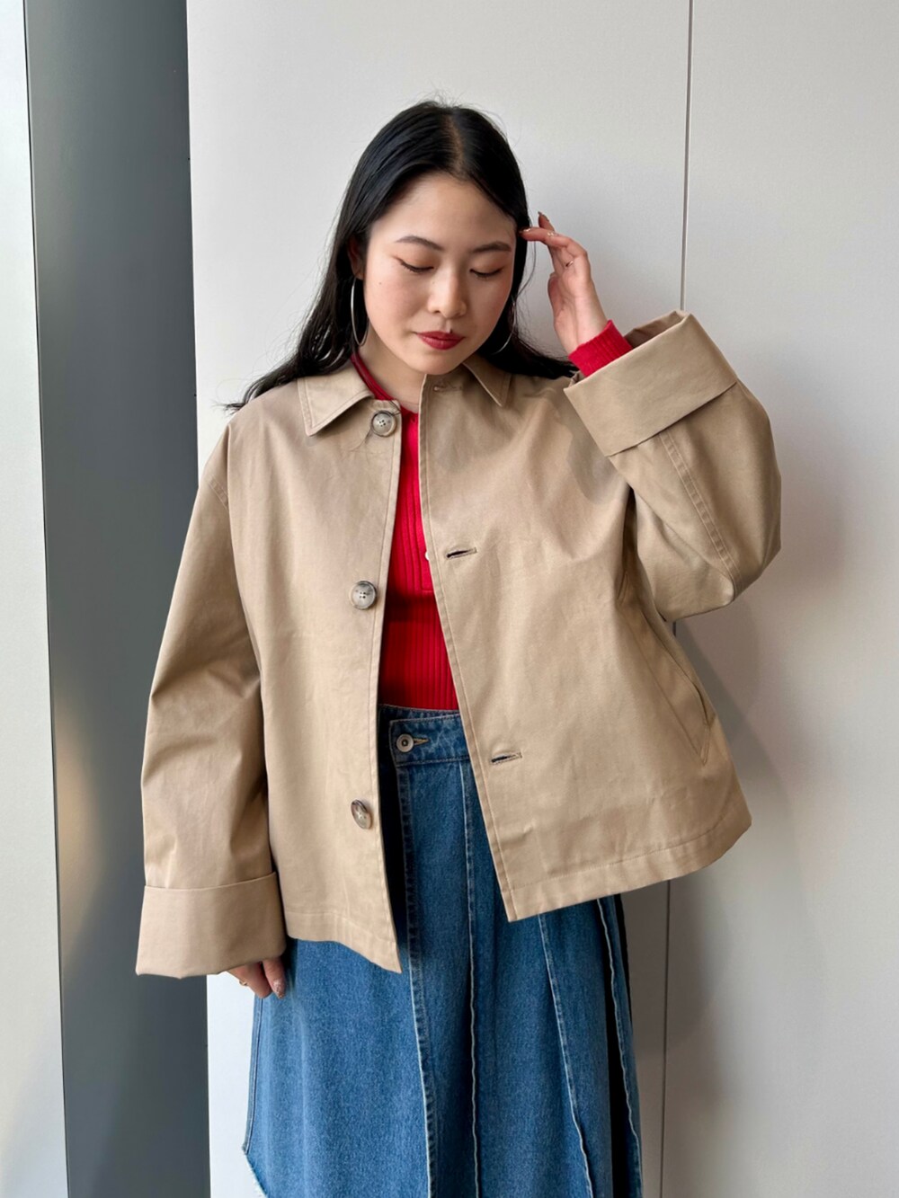 ベージュ系のその他アウター、レッド系のポロシャツ、ブルー系のデニムパンツを着用したレディースの春コーディネートの2枚目の写真