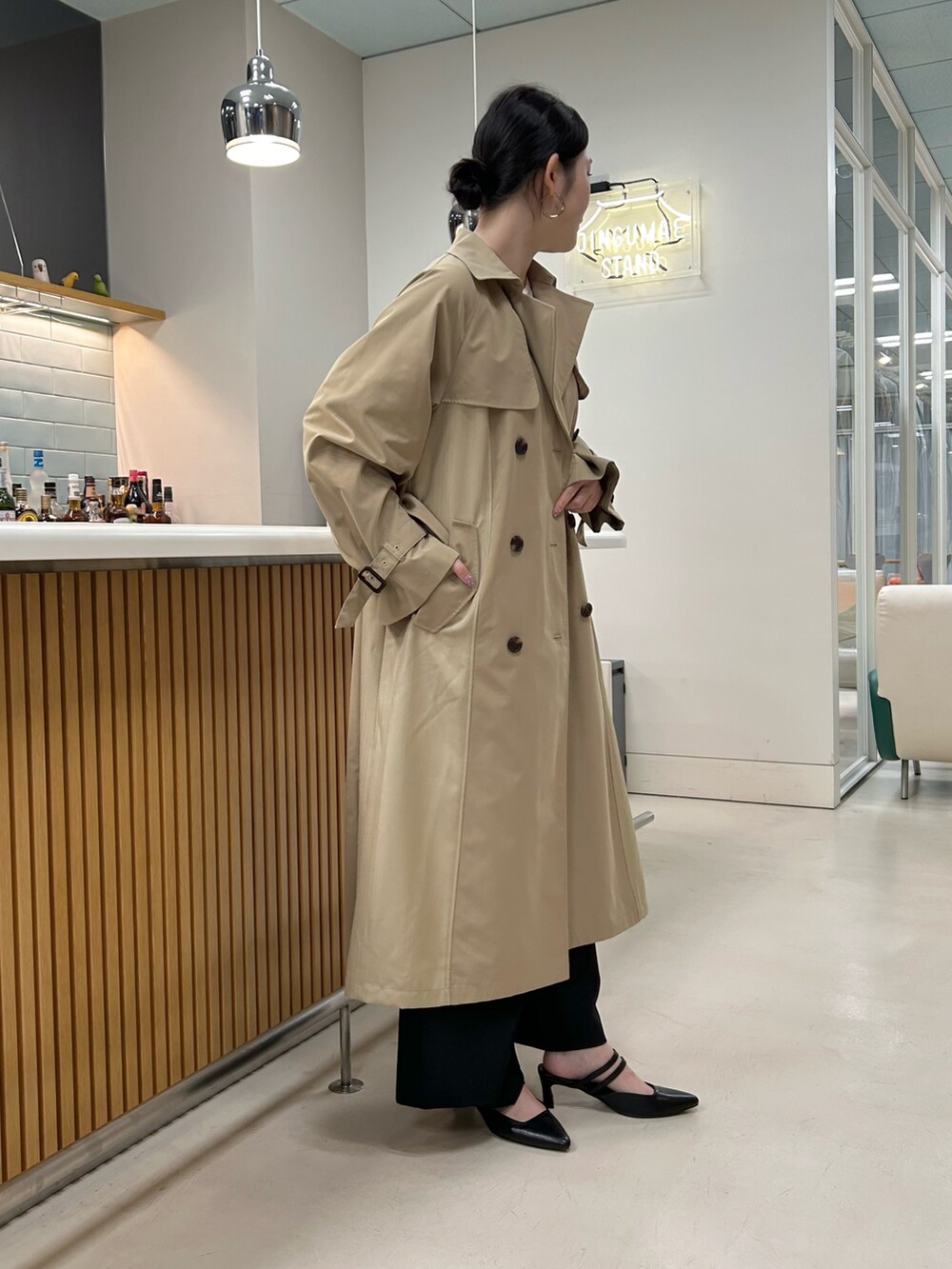 ベージュ系のトレンチコート、ホワイト系のTシャツ/カットソー、ブラック系のサンダルを着用したレディースの春コーディネートの2枚目の写真