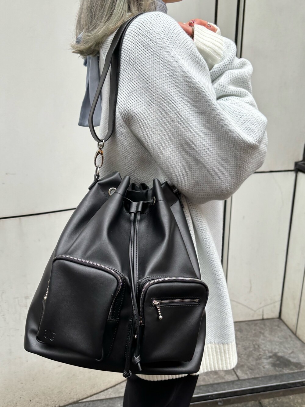 ホワイト系のニット/セーター、ブルー系のシャツ/ブラウス、ブラック系のバックパック/リュックを着用したレディースの春コーディネートの8枚目の写真